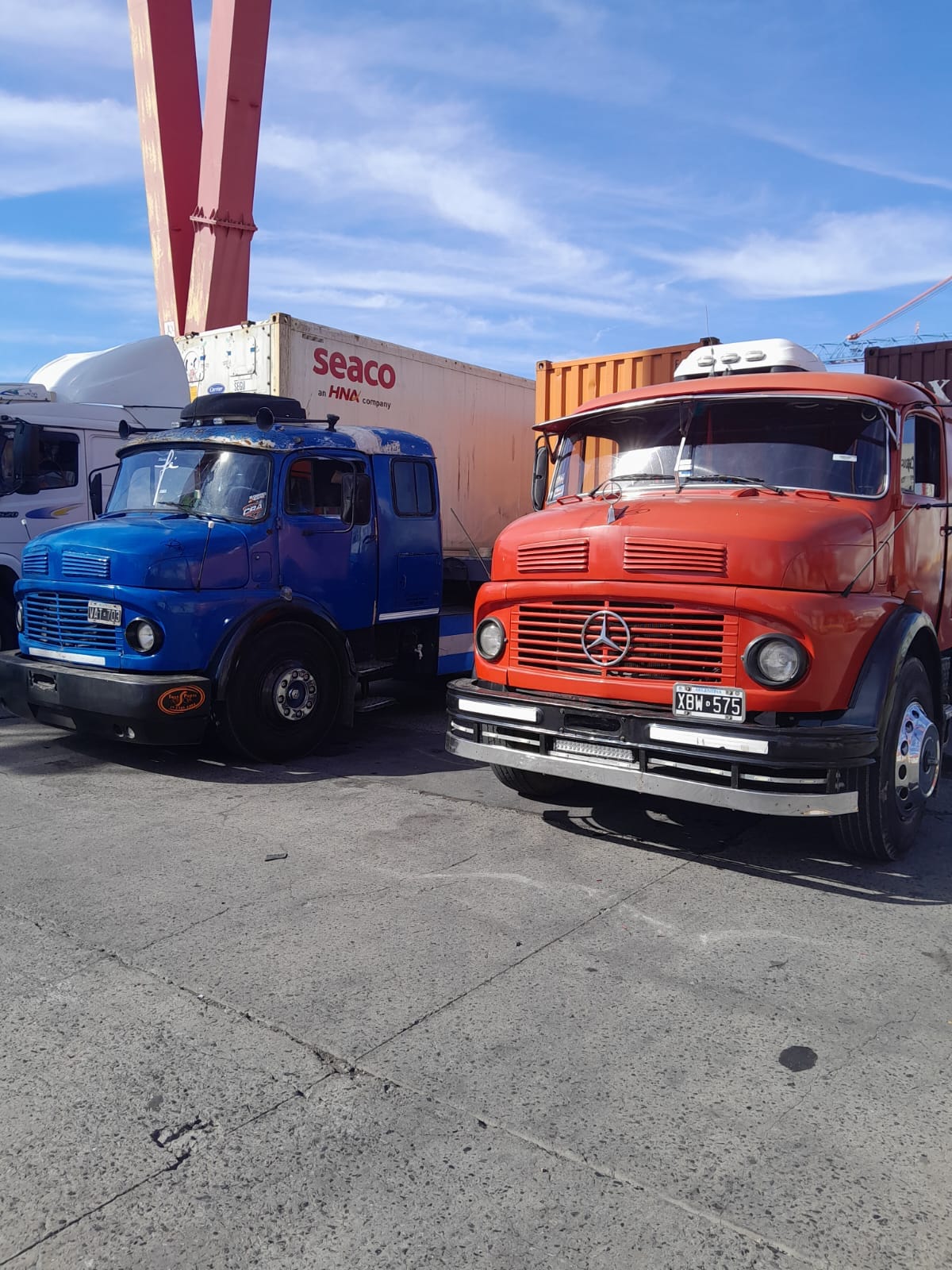 Dos camiones Mercedes-Benz 1114, uno azul y otro naranja, en la terminal portuaria